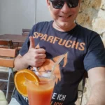 Bild von Stefan Noffke mit einem Glas Organgensaft und einem T-Shirt mit der Aufschrift Sparfuchs im Beitrag Corporate Identity